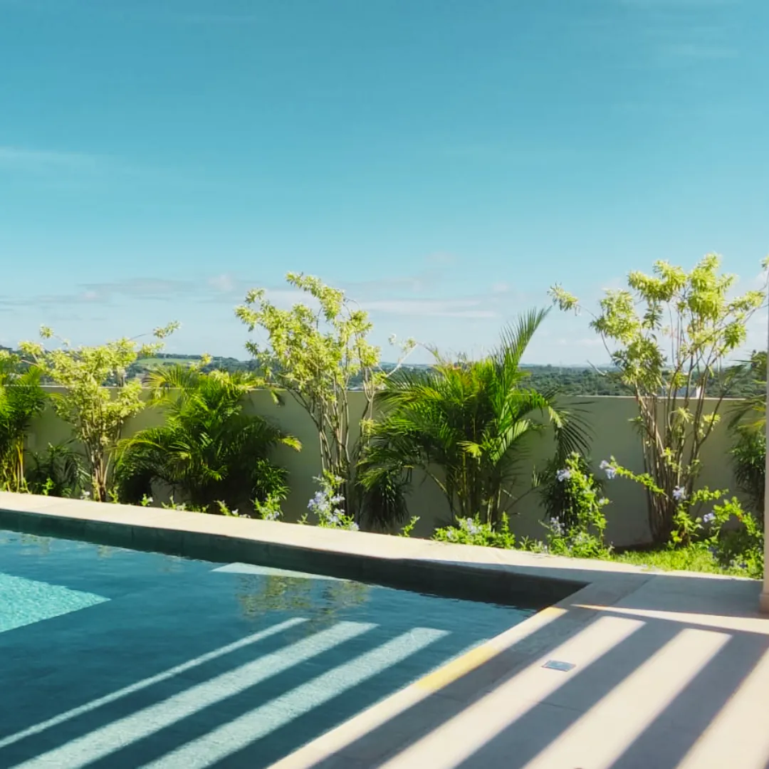 Área de piscina com jardim e palmeiras